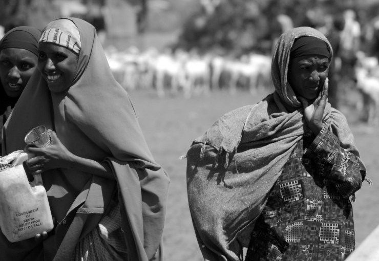 Women talk as their animals drink in East Africa.