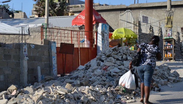 A woman walks by rubble after shopping in Delmas 18, Port au Prince.